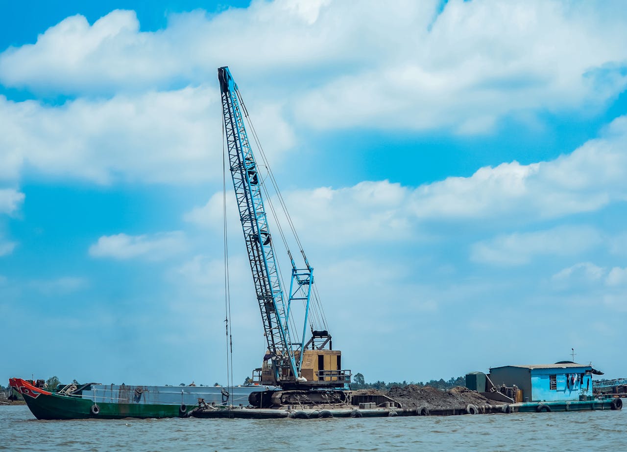 A crane barge stationed at a harbor under a partially cloudy sky, highlighting industrial maritime operations.